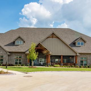 A large residential house with a stone facade and a spacious front yard.