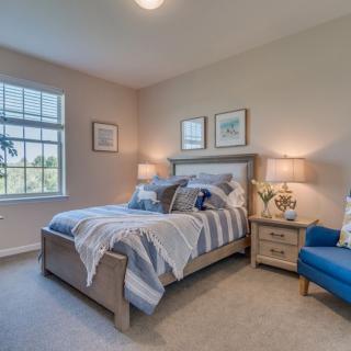 A cozy and well-decorated bedroom featuring a comfortable bed, elegant lamps, and tasteful artwork.