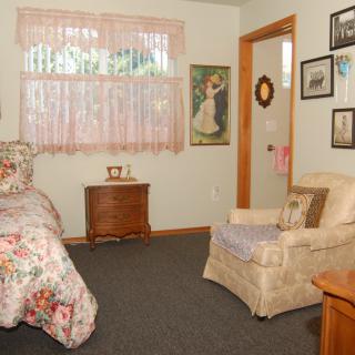 Cozy bedroom with floral decor, featuring an armchair and wall decorations.