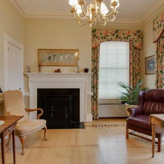 A traditional living room featuring a fireplace, elegant chandelier, and classic furniture.