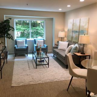 A cozy living room with modern decor, featuring a sofa, armchairs, and natural lighting.