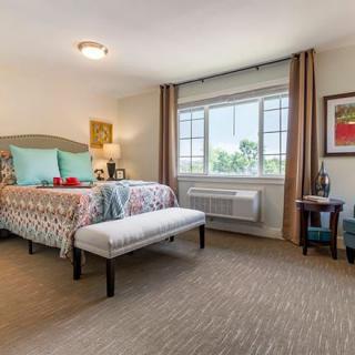 A well-decorated bedroom with a large window, colorful bedding, and stylish furnishings.