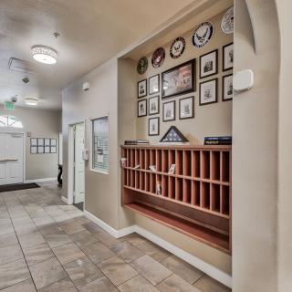 A hallway featuring framed pictures and a set of mail slots against a tiled floor.