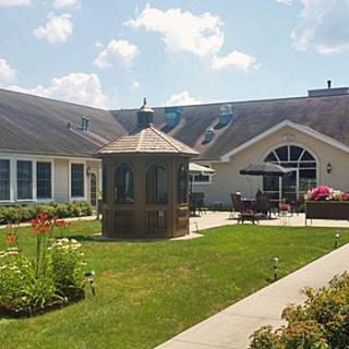 A well-maintained garden area with a gazebo, surrounded by buildings under a clear blue sky.