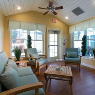 A cozy sunroom with comfortable seating, natural light, and soft yellow walls.