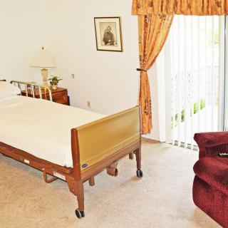A bedroom with a hospital bed, curtains, and furniture.