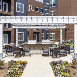 An outdoor patio area with a pergola and seating in an apartment complex.