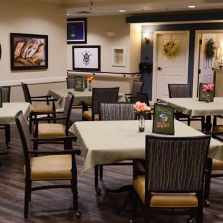 An indoor dining area with neatly arranged tables and chairs, decorated walls, and warm lighting.