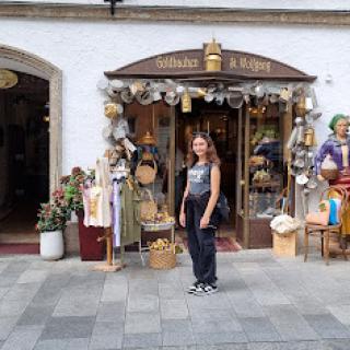 A woman standing in front of a charming craft store, showcasing local handmade goods.