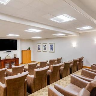 A well-designed home theater room with multiple rows of comfortable seating facing a large television screen.