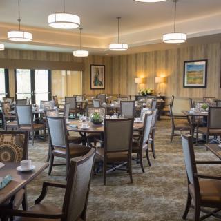 A spacious dining room with neatly arranged tables and chairs, elegant lighting, and tasteful decor.