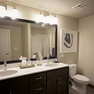 A modern bathroom with double sinks, a large mirror, and elegant lighting.