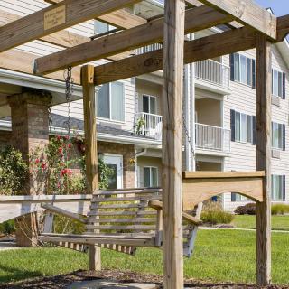A wooden swing set in front of an apartment building.