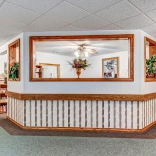A cozy reception area with wooden accents, ceiling fan, and decorative plants.