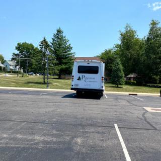 A parked bus in a spacious parking lot on a sunny day.