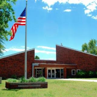 A school building displaying the American flag under a clear blue sky.