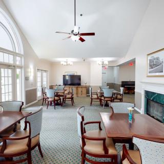 A spacious lounge area featuring multiple tables and chairs, a television, and a fireplace.