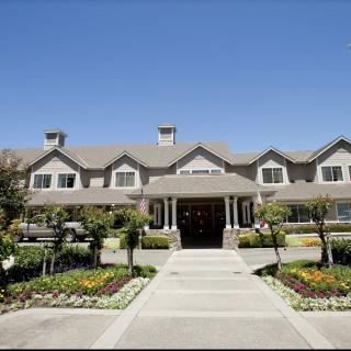 A large residential building with landscaped gardens and a clear blue sky.