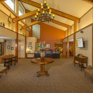 A warm and inviting hotel lobby with a chandelier, wooden beams, and reception desk.