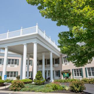 A building entrance with large white columns and surrounding greenery.