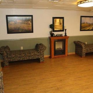 A cozy waiting area featuring two patterned benches, a decorative fireplace, and framed artwork on the walls.
