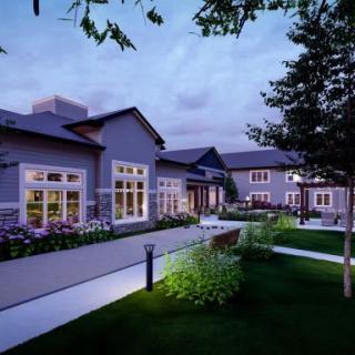 A modern building surrounded by a landscaped garden at dusk.