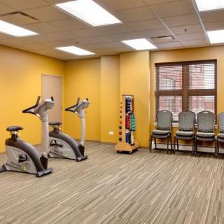 A small gym room with exercise bikes, chairs, and a window.