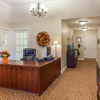 A well-organized office reception area with a wooden desk and comfortable chairs, adorned with decorative items and warm lighting.