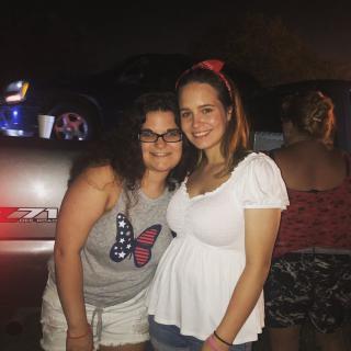 Two friends smiling at an outdoor night gathering.