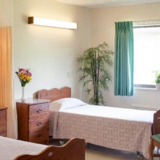 A cozy, well-lit bedroom featuring twin beds, wooden furniture, and a floral arrangement.