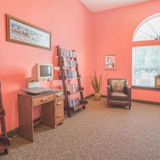 A cozy waiting area featuring vibrant pink walls, a computer desk, comfortable seating, and a magazine rack.