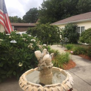 A beautifully landscaped garden featuring a decorative fountain and an American flag.