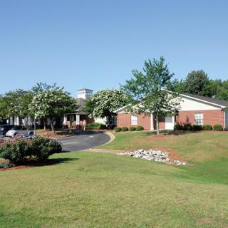 A sunny day view of a building surrounded by a well-maintained lawn and trees.