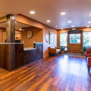 A bright and welcoming reception lobby with wood flooring, a front desk, and seating area.