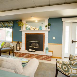 A cozy living room with a modern design featuring a brick fireplace and blue accent walls.