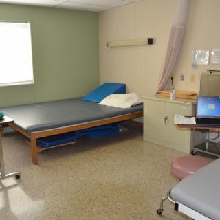 A hospital patient room equipped with a bed, medical equipment, and natural light from a nearby window.