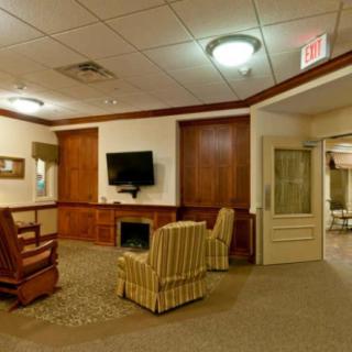 A cozy lobby area featuring a television, comfortable seating, and warm wood paneling.