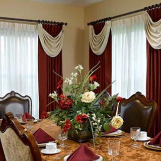 A beautifully set dining table with an elegant flower arrangement and luxurious drapery.