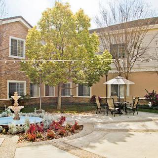 A peaceful courtyard featuring a fountain, outdoor seating, and lush landscaping.