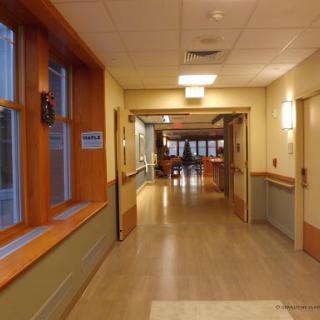A well-lit hallway featuring large windows and wooden accents.