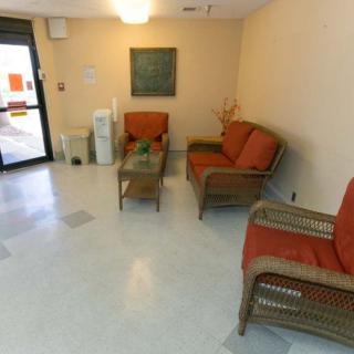 A small waiting room with wicker chairs and a sofa, featuring a glass coffee table and neutral decor.