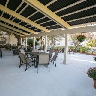 An outdoor patio with tables and chairs under a covered area.