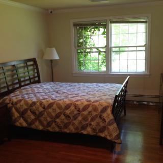 A cozy bedroom with a bed, lamp, and large window.