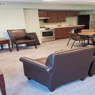 A cozy living room with a connected kitchen area featuring modern furniture and appliances.