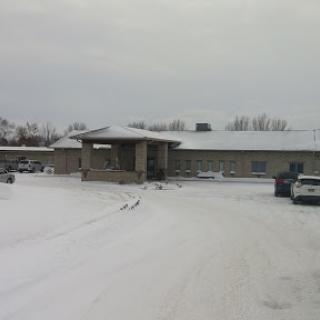 A snowy scene featuring a building and vehicles amidst winter weather.