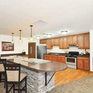A modern kitchen with wooden cabinets, a central island, and stainless steel appliances.