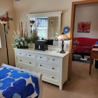 A cozy bedroom setup featuring a white dresser with a mirror and decorative elements.