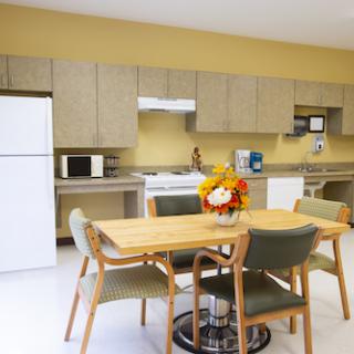 A modern kitchen and dining area featuring a wooden table with four chairs, surrounded by essential kitchen appliances.