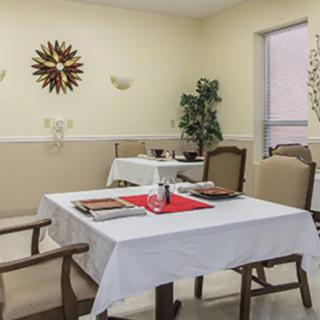 A neatly arranged dining area with tables and chairs, featuring decorative elements and a clock on the wall.