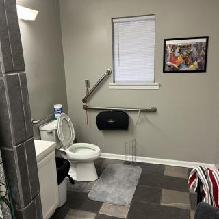 An accessible bathroom with a toilet, sink, and handrails.